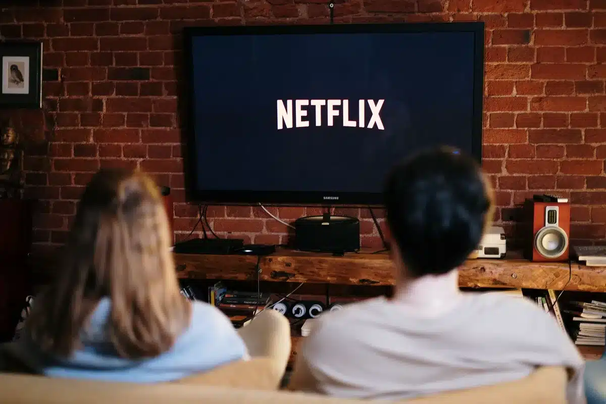 Une personne regardant une série en binge-watching, relaxée sur son canapé avec des snacks.