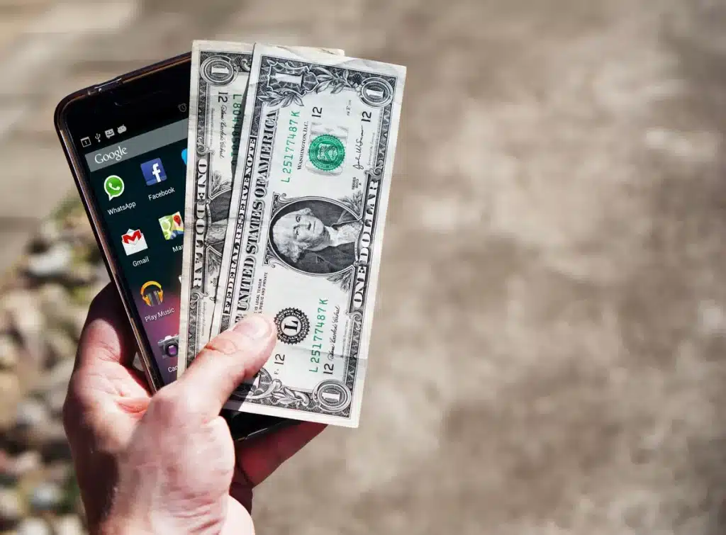 Mains tenant un téléphone affichant une interface de portefeuille numérique avec des transactions cryptographiques