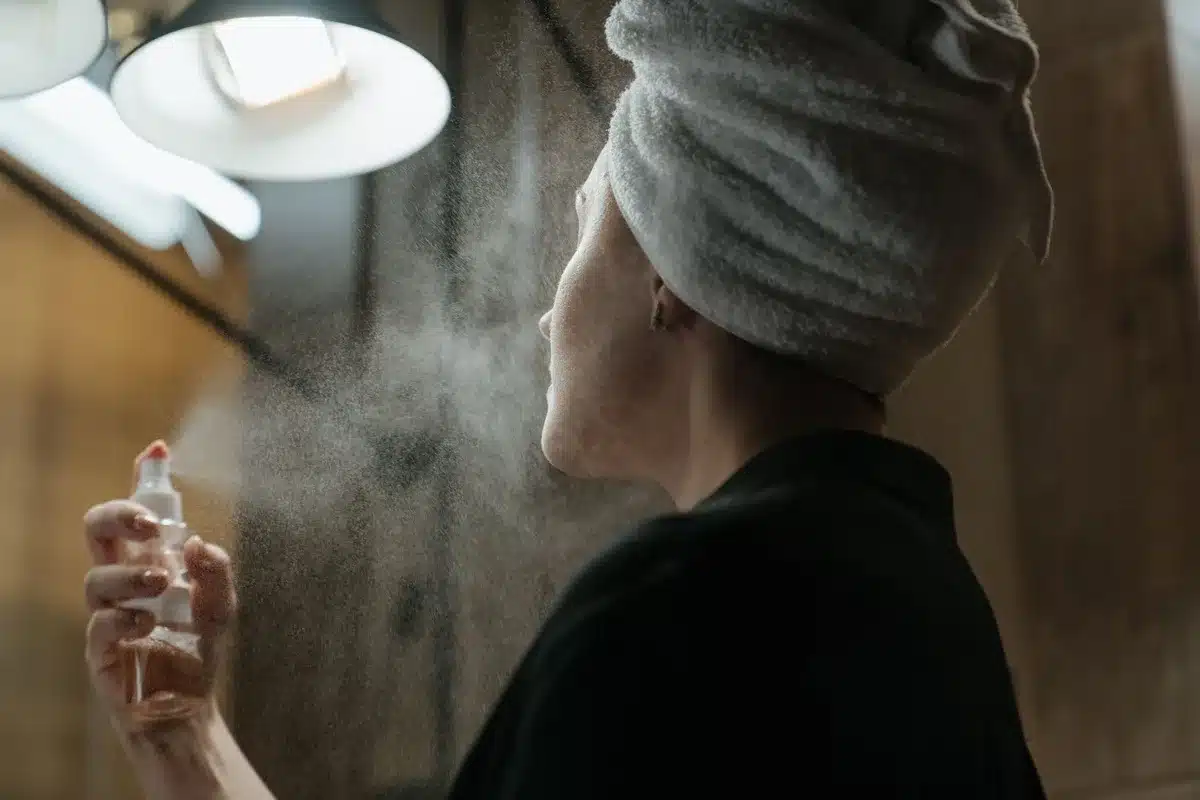 Personne portant des vêtements clairs utilisant un spray d'eau ou une serviette froide pour se rafraîchir