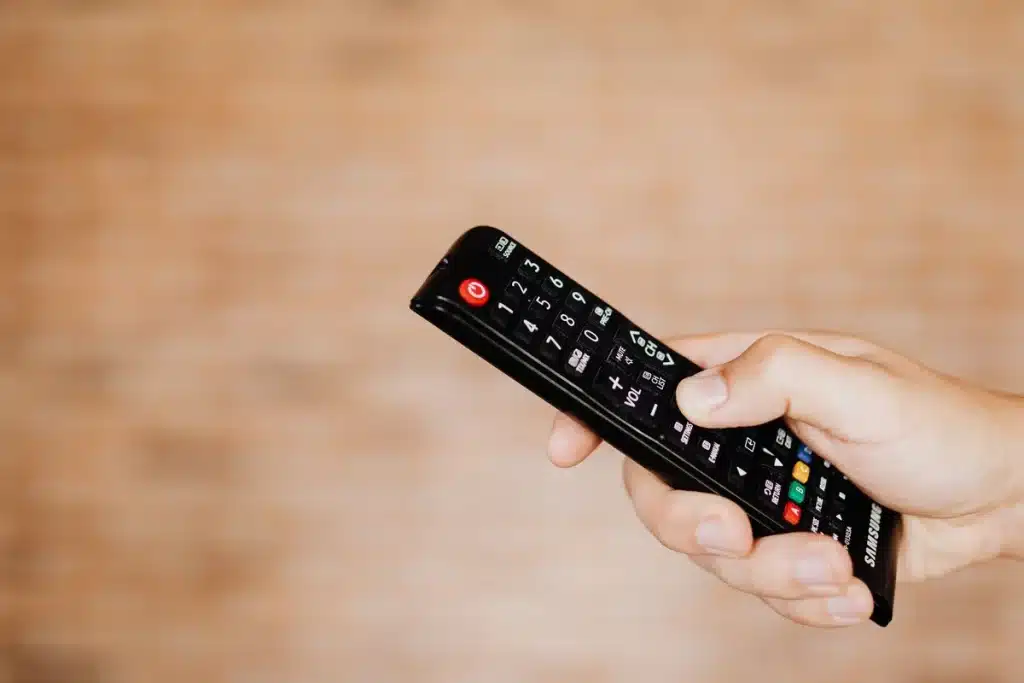 Main holding a remote control while watching a football match on television
