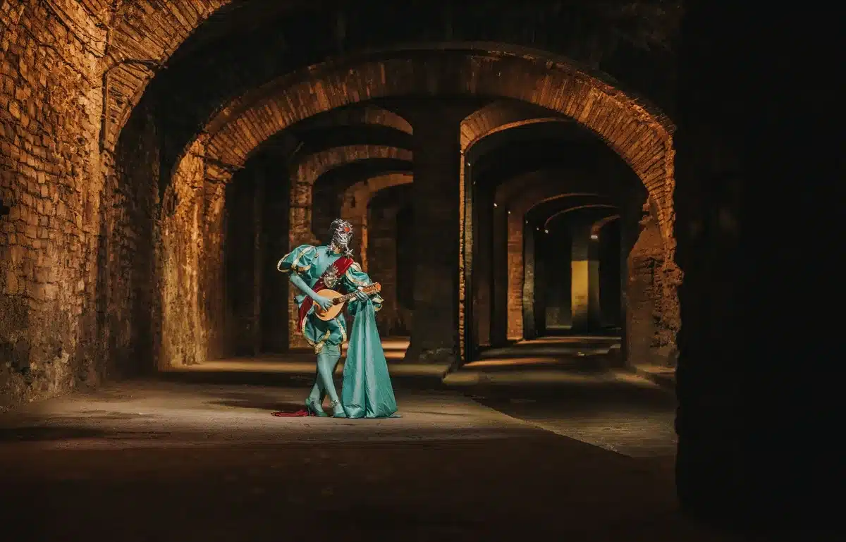 Scène de série d'époque avec costumes colorés et décors fantaisistes, montrant une atmosphère ludique et subversive.