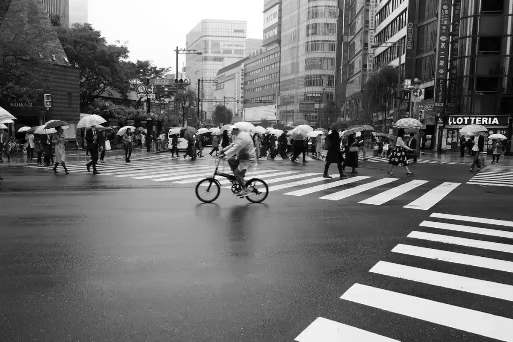 Sac à dos étanche posé sur le sol mouillé près d'un vélo par temps de pluie en milieu urbain