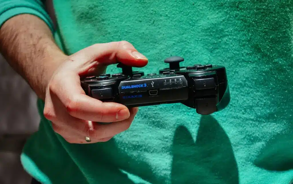Mains tenant une manette de jeu devant un écran sombre avec des logos Nintendo