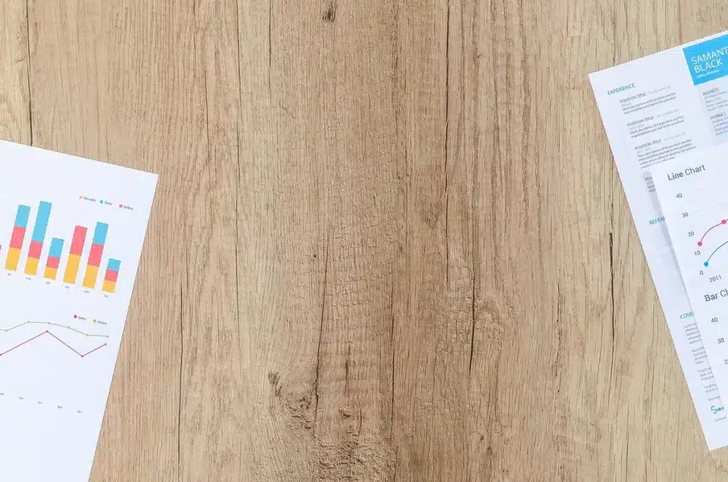 Mains feuilletant un dossier de développement de jeu sur une table baignée de lumière du jour