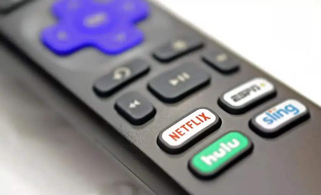 Personne regardant un écran de télévision avec une télécommande, dans un éclairage tamisé en soirée