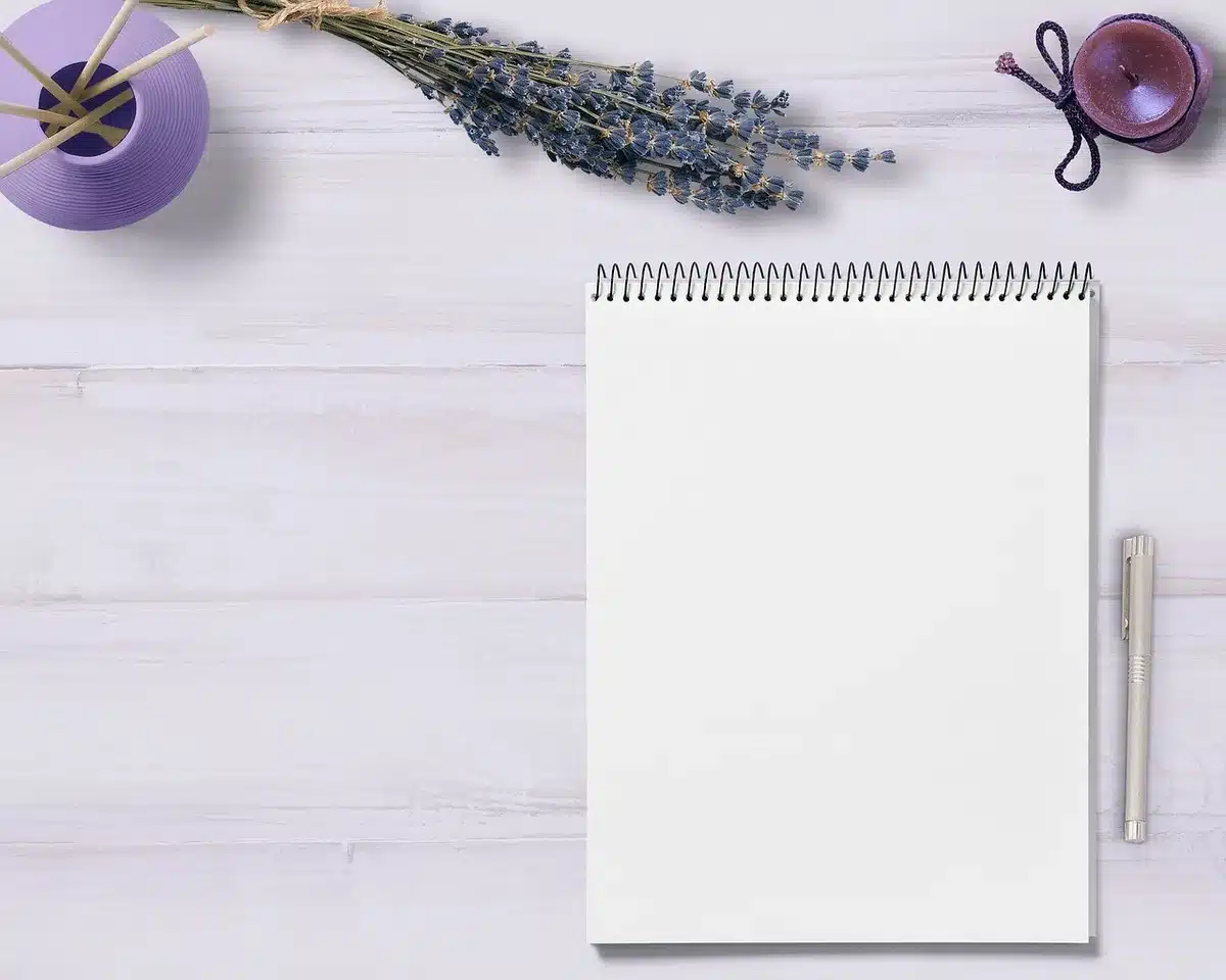 Main écrivant des notes à côté d'un ordinateur portable affichant un e‑mail