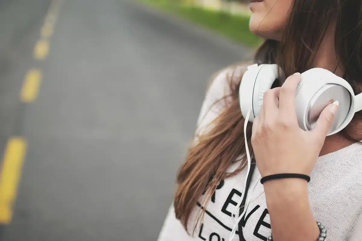 Personne avec écouteurs et transcription floue à l'écran illustrant le résumé audio