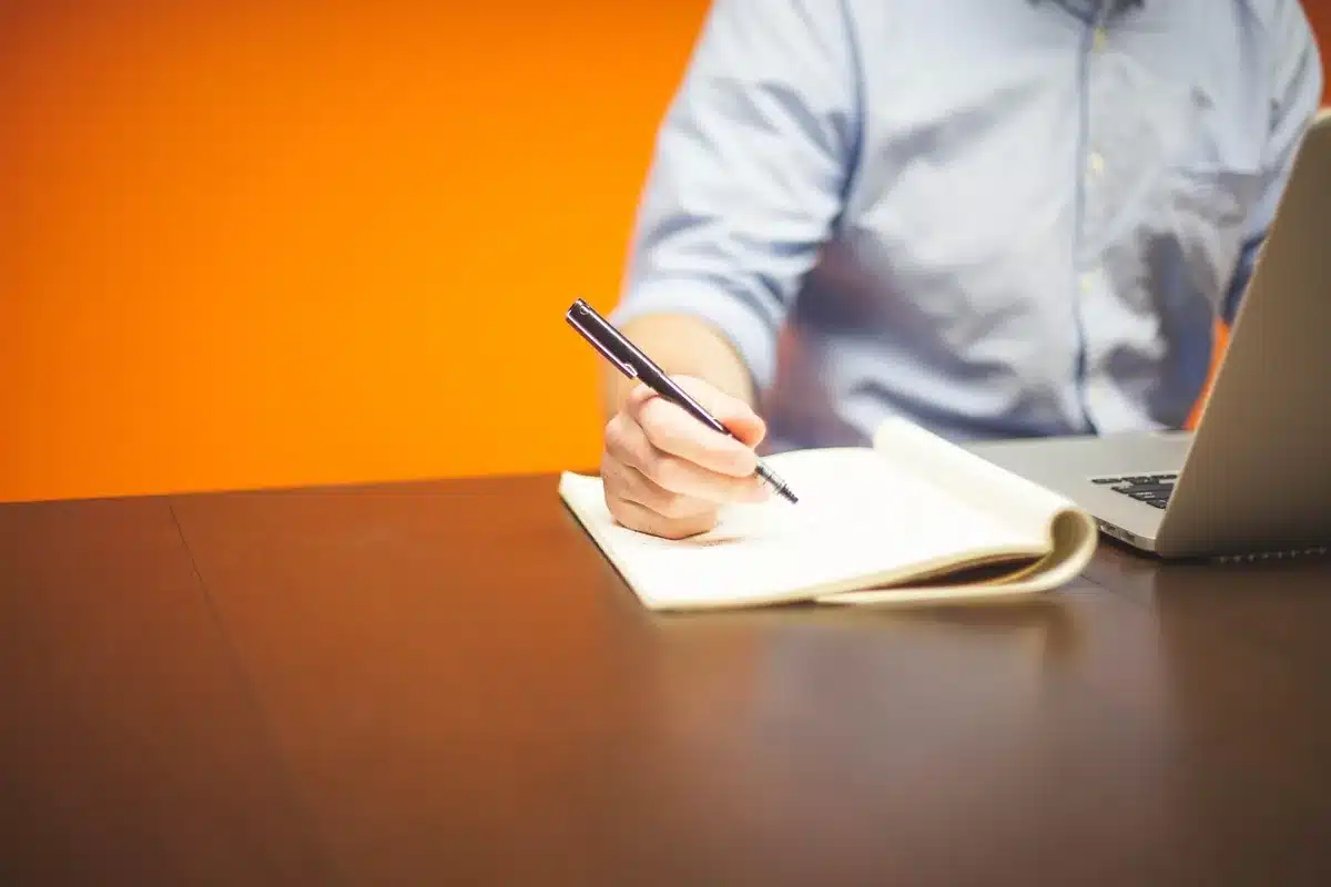 Employé mettant à jour son CV sur ordinateur près d'une fenêtre en plein jour
