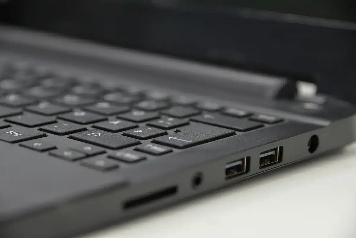 Main préparant une clé USB bootable à côté d'un ordinateur portable en journée
