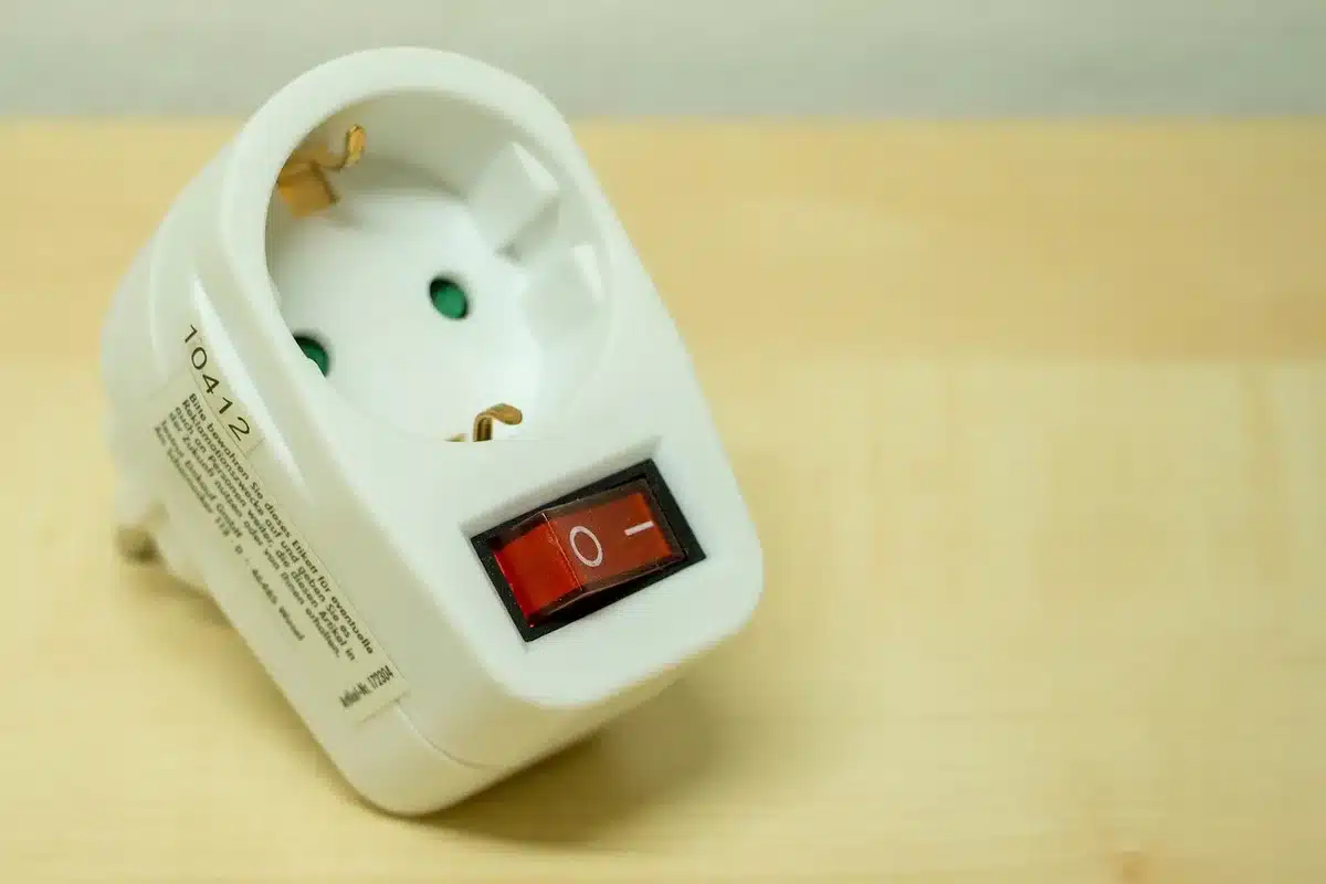 Adaptateur CPL branché sur une prise murale près d'un routeur avec câble Ethernet