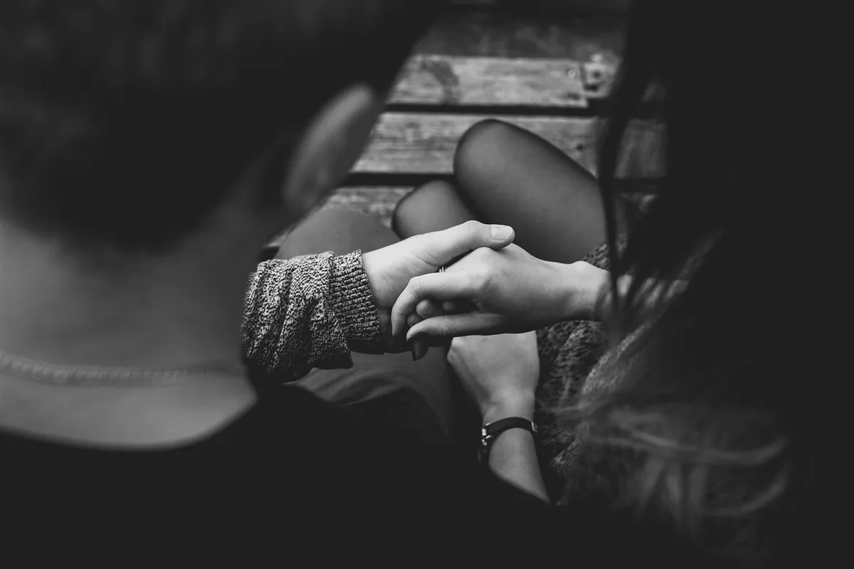 Close-up of an anonymous hand holding a folded smartphone, screen glowing but no logos visible