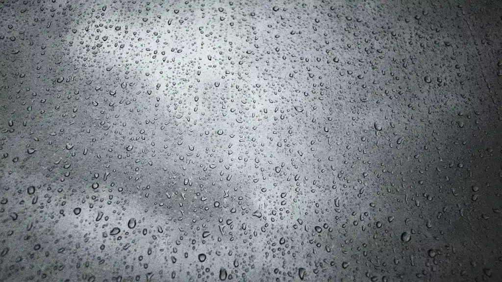 Veste imperméable suspendue dans une entrée avec gouttes d'eau et chaussures humides