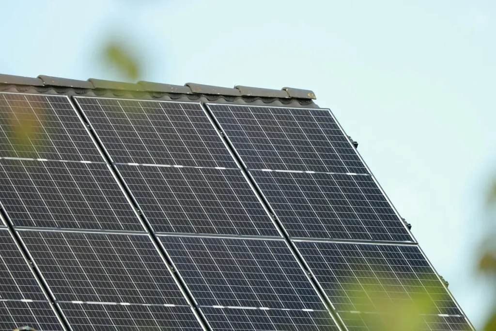 Le solaire peut-il réduire vos factures d’énergie ? Toit résidentiel en plein jour avec panneaux solaires et mains anonymes ajustant une installation