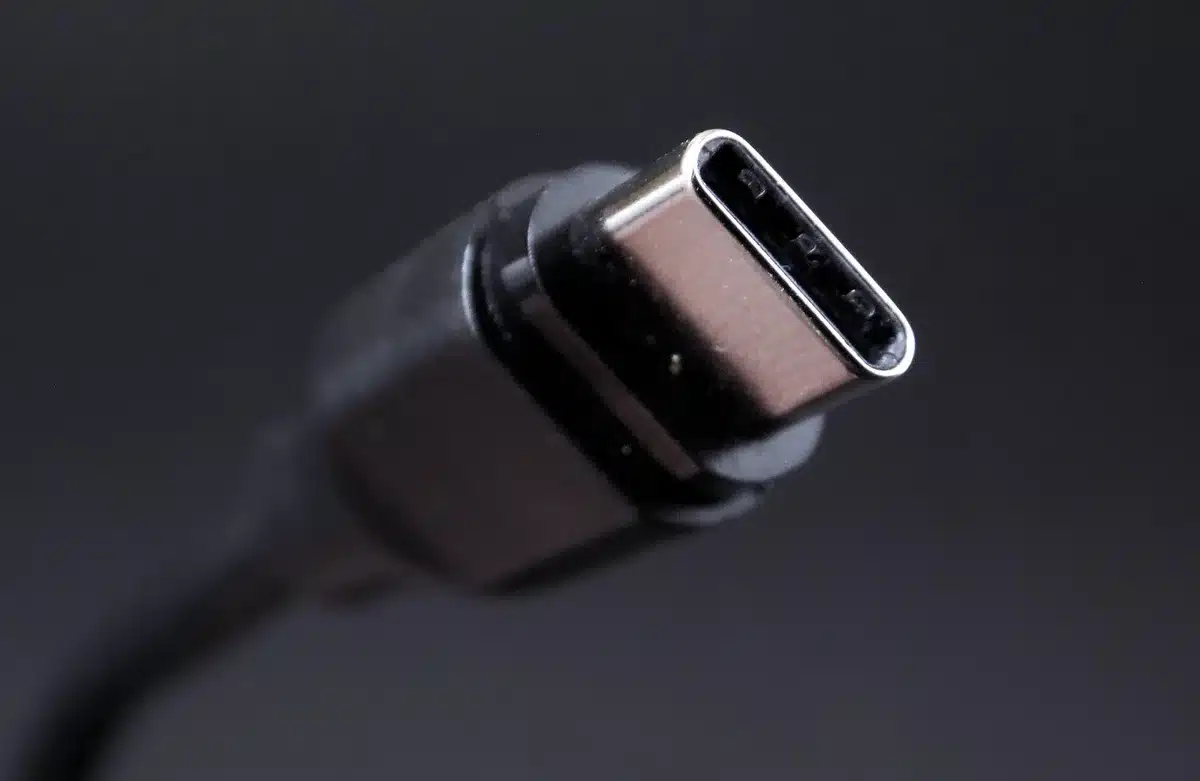 Close-up of a generic USB-C braided cable coiled beside an unbranded compact wall charger on a wooden table
