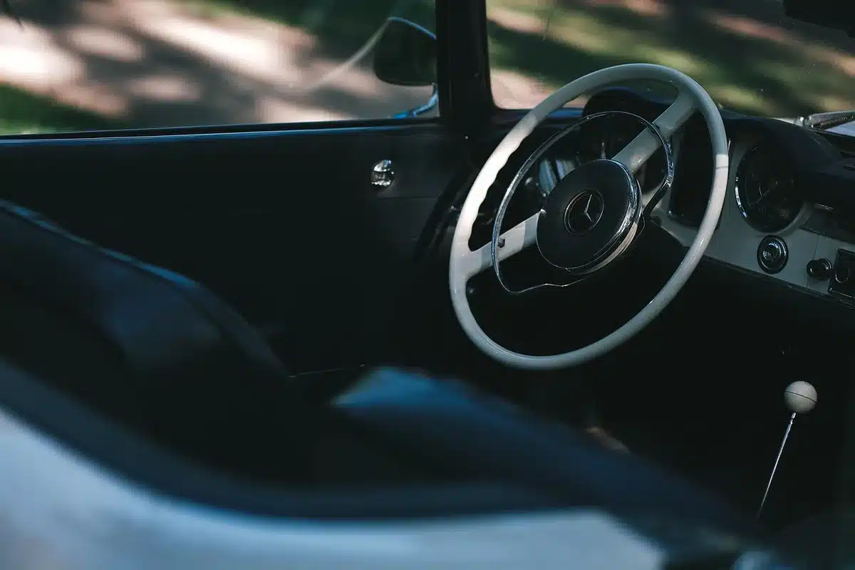 Mains sur le volant et tableau de bord d'une voiture en journée