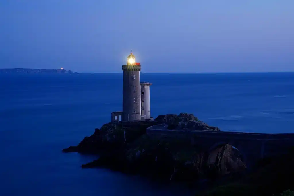 Île brumeuse avec phare et petit téléviseur portable sur un rocher